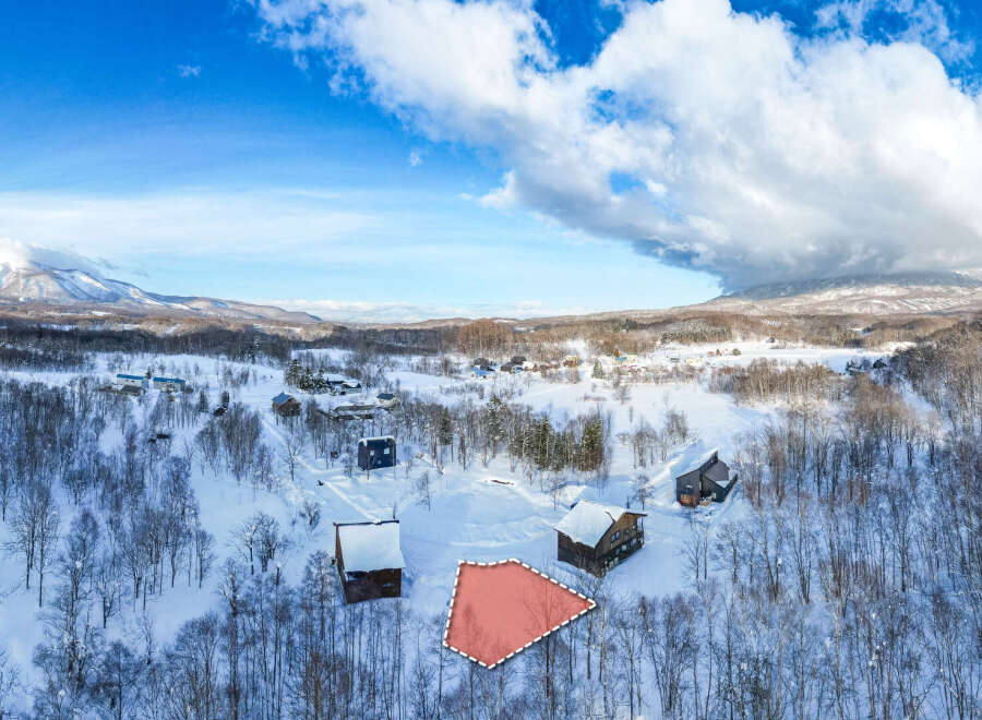 This stunning property boasts a unique triangular lot nestled in a serene snowy landscape, surrounded by charming winter homes and breathtaking mountain views.