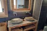 This stunning bathroom boasts a rustic charm with its wooden vanity and stone sinks.