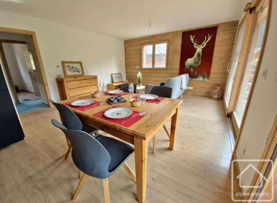 This charming property features a cozy dining area with a wooden table and stylish chairs, perfect for enjoying meals.