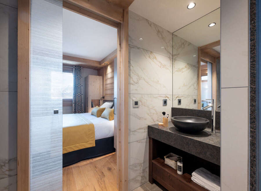 This stunning bathroom boasts a sleek, modern design with marble tiling and a dark granite countertop.