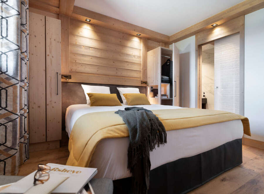 This stunning bedroom boasts a cozy and luxurious atmosphere, featuring a plush bed with a mustard yellow throw and a dark gray knit blanket.
