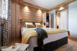 This stunning bedroom boasts a cozy and luxurious atmosphere, featuring a plush bed with a mustard yellow throw and a dark gray knit blanket.