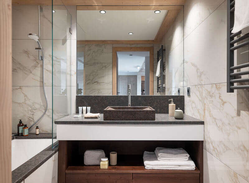 This luxurious bathroom boasts a spacious design with marble tiling, a large walk-in shower, and a modern double vanity with ample storage.
