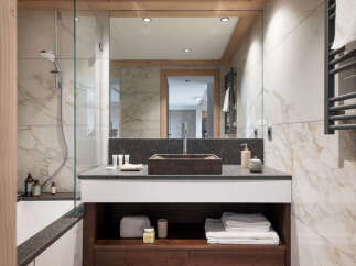 This luxurious bathroom boasts a spacious design with marble tiling, a large walk-in shower, and a modern double vanity with ample storage.