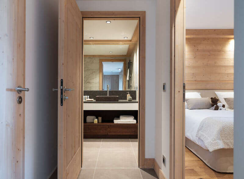 This stunning hallway boasts a sleek design with light grey tile flooring and light wood doors and trim.
