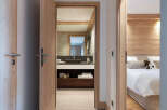 This stunning hallway boasts a sleek design with light grey tile flooring and light wood doors and trim.