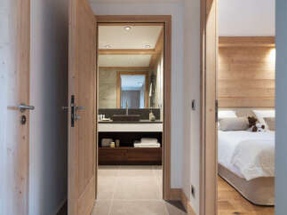 This stunning hallway boasts a sleek design with light grey tile flooring and light wood doors and trim.