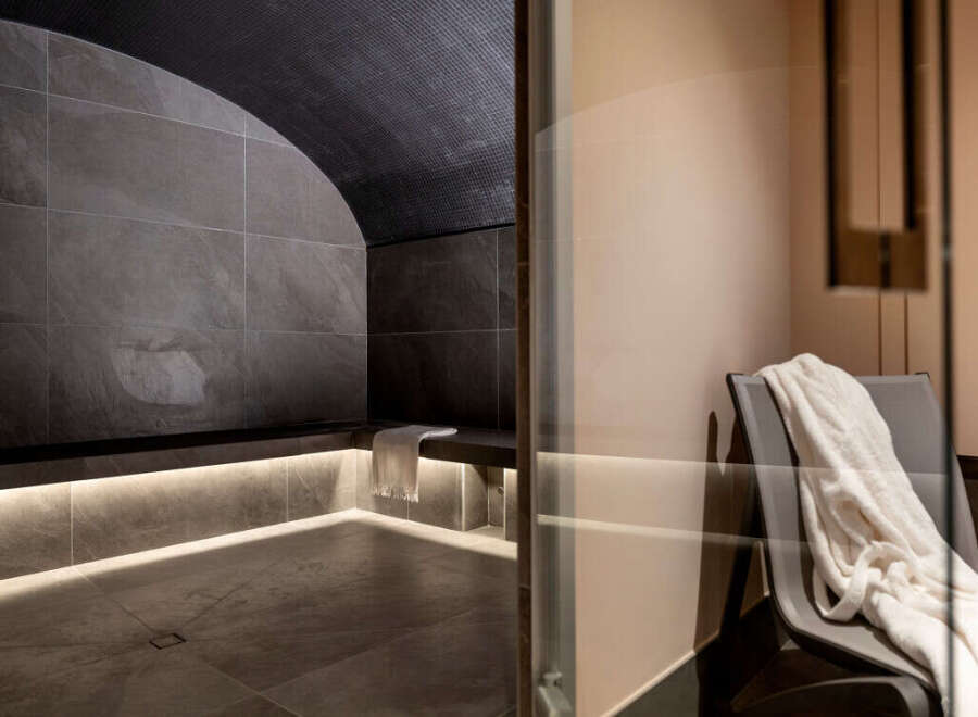 Indulge in ultimate relaxation in this luxurious private spa, featuring a sleek, modern steam room with a calming grey stone design and ambient lighting.