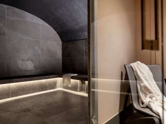 Indulge in ultimate relaxation in this luxurious private spa, featuring a sleek, modern steam room with a calming grey stone design and ambient lighting.