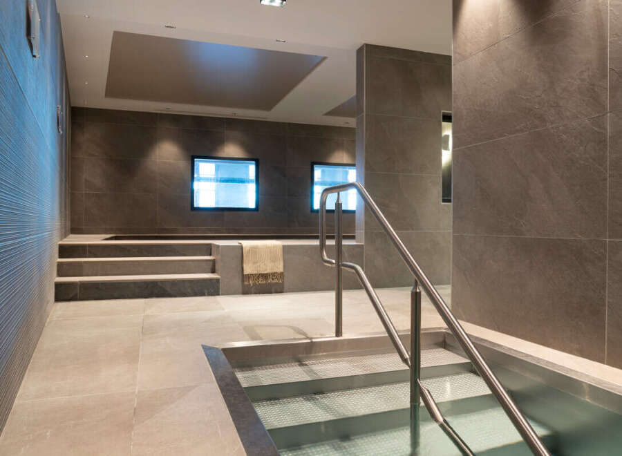 This luxurious spa features a stunning, modern design with sleek gray stone tiles and stainless steel accents.