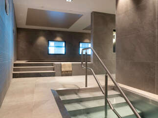 This luxurious spa features a stunning, modern design with sleek gray stone tiles and stainless steel accents.
