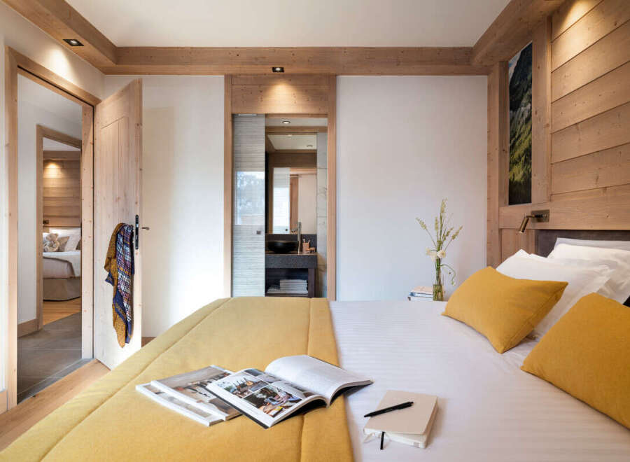 Experience luxury living in this stunning bedroom, featuring a cozy bed with vibrant yellow pillows and a matching bedspread.