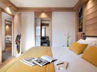 Experience luxury living in this stunning bedroom, featuring a cozy bed with vibrant yellow pillows and a matching bedspread.