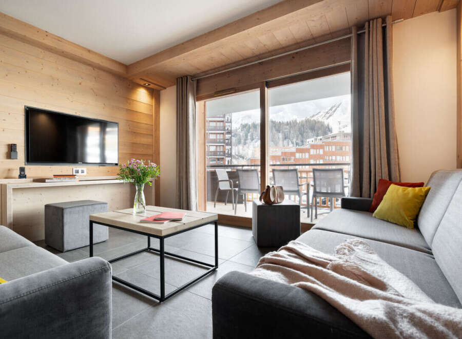 Experience luxury living in this stunning property, featuring a modern living room with a large TV and a cozy sofa.