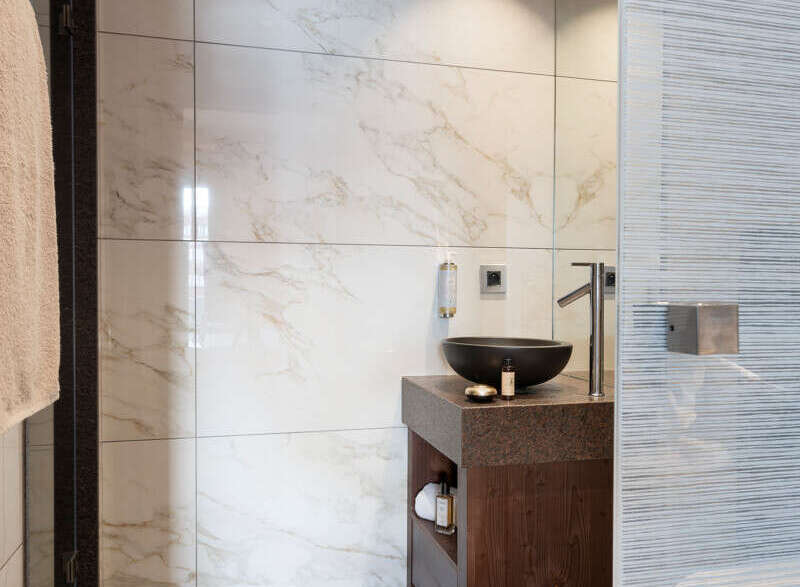 This luxurious bathroom features a modern design with marble tiles and a sleek, dark wood vanity.