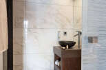 This luxurious bathroom features a modern design with marble tiles and a sleek, dark wood vanity.