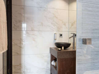 This luxurious bathroom features a modern design with marble tiles and a sleek, dark wood vanity.