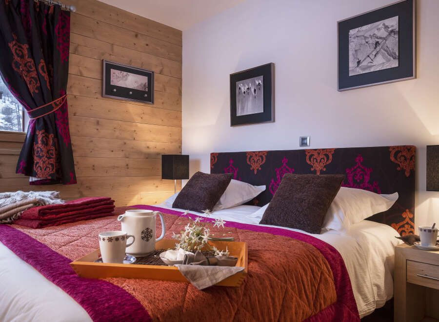 Cozy bedroom with wooden walls and a comfortable double bed, featuring a warm color scheme and stylish decor.