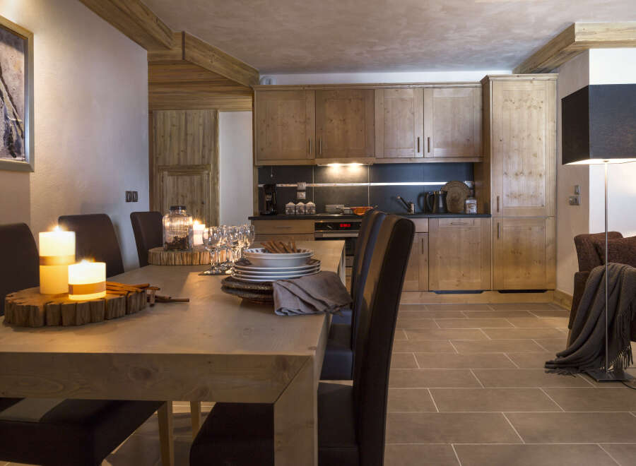 This stunning chalet boasts a spacious open-plan living area with a rustic wooden dining table, perfect for intimate gatherings.