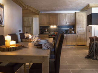 This stunning chalet boasts a spacious open-plan living area with a rustic wooden dining table, perfect for intimate gatherings.