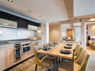 This stunning apartment boasts a modern, open-plan kitchen with high-end appliances and ample counter space, seamlessly flowing into a spacious dining area perfect for entertaining.