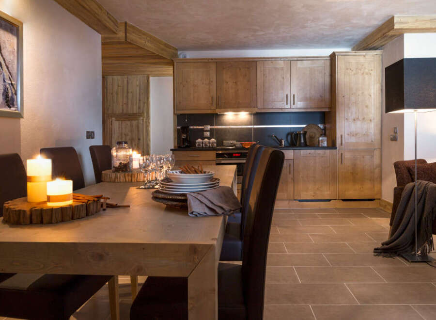 This stunning chalet boasts a spacious, light-filled dining area with a rustic wooden table, perfect for enjoying meals with loved ones.