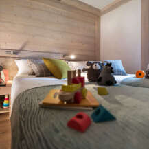 Cozy bedroom with twin beds, wooden wall paneling, and a playful atmosphere.