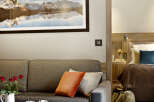 Relax in this cozy living room featuring a comfortable sofa, a rustic coffee table, and a stunning mountain landscape print.