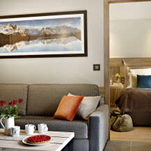 Relax in this cozy living room featuring a comfortable sofa, a rustic coffee table, and a stunning mountain landscape print.