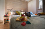Cozy bedroom with twin beds, wooden wall paneling, and a playful atmosphere.