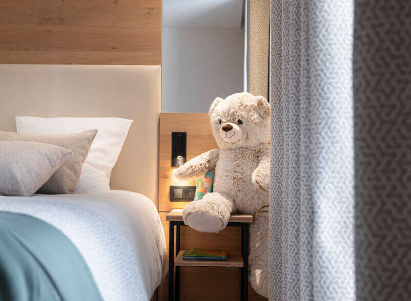 Cozy bedroom with a wooden headboard and a plush teddy bear sitting on a bedside table.