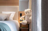 Cozy bedroom with a wooden headboard and a plush teddy bear sitting on a bedside table.
