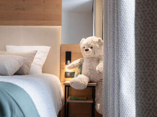 Cozy bedroom with a wooden headboard and a plush teddy bear sitting on a bedside table.