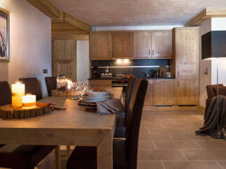 This stunning chalet boasts a spacious, light-filled dining area with a rustic wooden table, perfect for enjoying meals with loved ones.