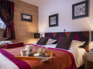 Cozy bedroom with wooden walls and a comfortable double bed, featuring a warm color scheme and stylish decor.
