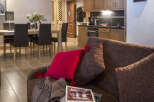 This stunning apartment boasts an open-plan living area with a comfortable brown couch, perfect for relaxing after a day on the slopes.