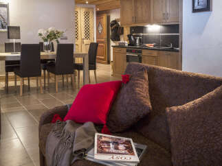 This stunning apartment boasts an open-plan living area with a comfortable brown couch, perfect for relaxing after a day on the slopes.