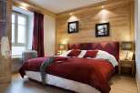 This luxurious bedroom boasts a king-size bed with plush red bedding, complemented by rich burgundy curtains and patterned headboard.