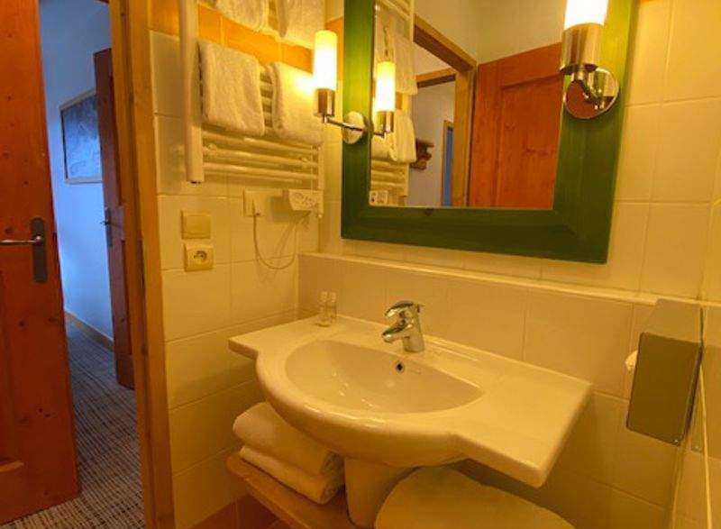 This charming bathroom features a stylish green-framed mirror and warm lighting, creating a cozy atmosphere.