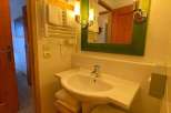 This charming bathroom features a stylish green-framed mirror and warm lighting, creating a cozy atmosphere.