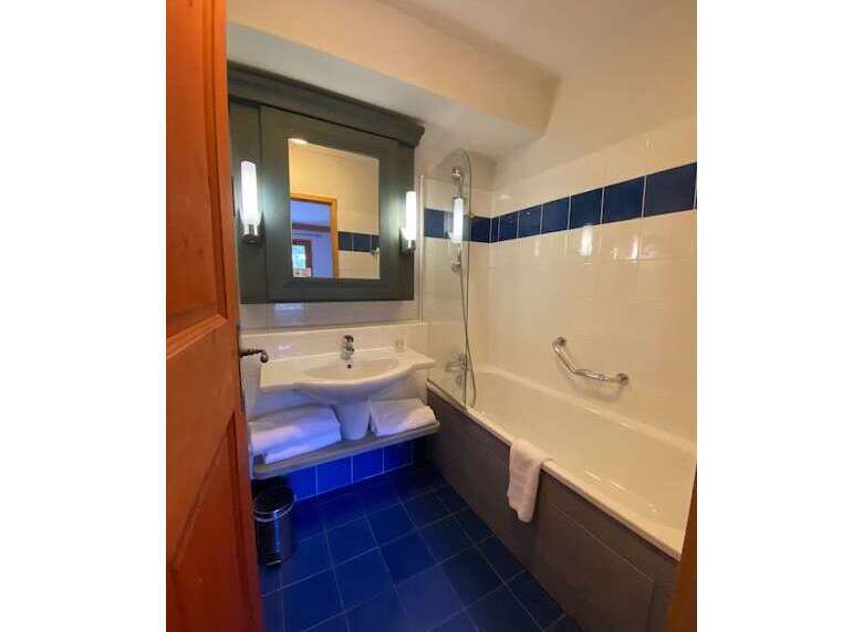 This charming bathroom features a spacious bathtub with a convenient grab bar, perfect for a relaxing soak.