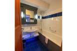 This charming bathroom features a spacious bathtub with a convenient grab bar, perfect for a relaxing soak.