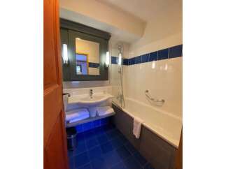 This charming bathroom features a spacious bathtub with a convenient grab bar, perfect for a relaxing soak.