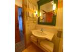 This charming bathroom features a modern sink with ample counter space, complemented by a stylish green-framed mirror and elegant wall sconces.