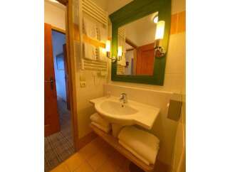 This charming bathroom features a modern sink with ample counter space, complemented by a stylish green-framed mirror and elegant wall sconces.