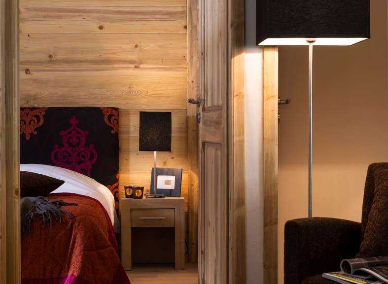 This stunning bedroom boasts a cozy and luxurious atmosphere, featuring rich wood paneling and a plush bed with a vibrant red coverlet.