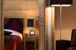 This stunning bedroom boasts a cozy and luxurious atmosphere, featuring rich wood paneling and a plush bed with a vibrant red coverlet.
