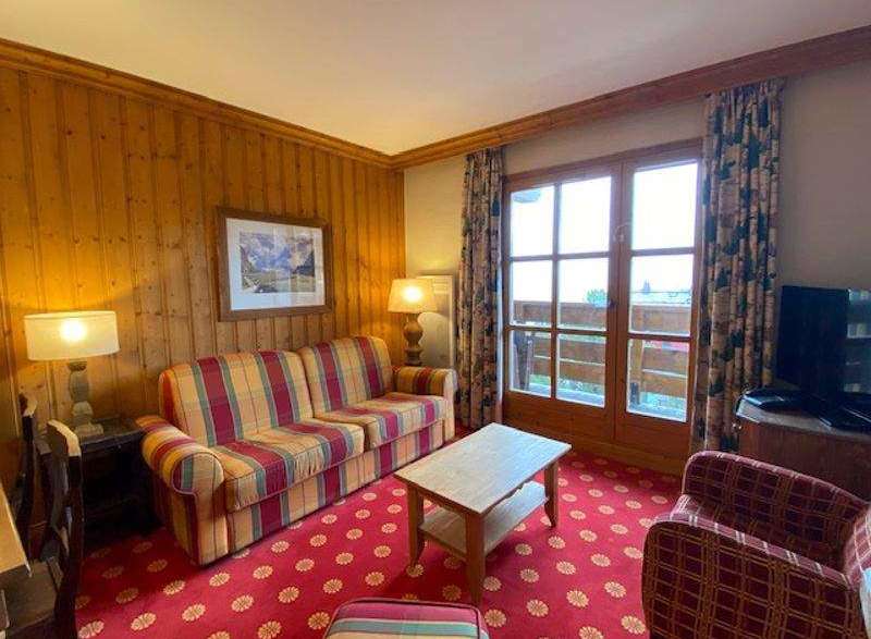 Cozy living room with a vibrant red patterned carpet and a comfortable plaid sofa.