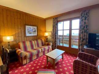 Cozy living room with a vibrant red patterned carpet and a comfortable plaid sofa.