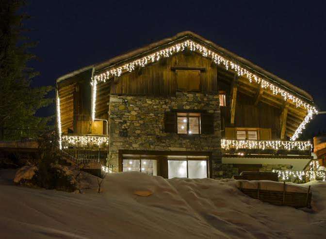 This stunning chalet boasts a beautiful stone and wood exterior, illuminated by charming icicle lights.